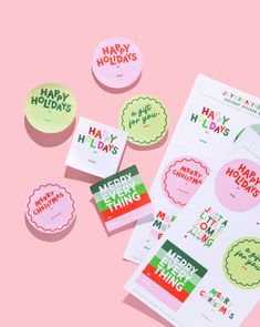 various stickers on pink background with happy holidays written in different colors and shapes, including the words merry everything