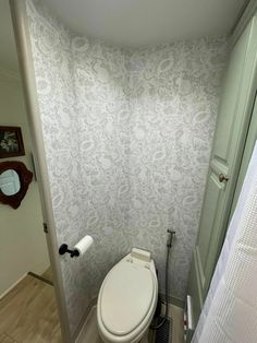 a white toilet sitting in a bathroom next to a shower stall with a curtain on it