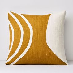 an orange and white pillow with wavy lines on the front, against a white wall