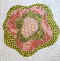 a close up of a quilted object on a white surface with green and pink circles