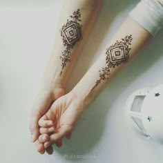 two people holding hands with tattoos on their arms and wrist, one has a diamond tattoo