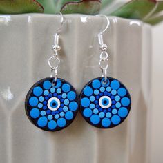 a pair of blue and black earrings sitting on top of a white potted plant