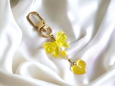 a yellow flower and heart charm on a white satin background with a gold metal keychain