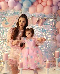 a mother and daughter standing in front of balloons