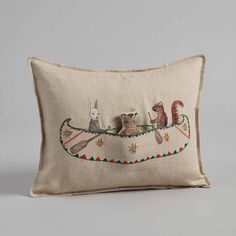 an embroidered pillow with animals in a boat on the front and sides, sitting against a gray background