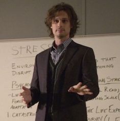 a man standing in front of a whiteboard with writing on the wall behind him