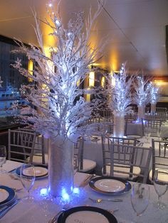 the centerpieces are decorated with white branches and blue lights