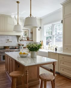 a kitchen island with two stools next to it and a bowl of fruit on the counter