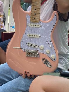 a pink guitar is sitting on someone's lap in front of the camera man