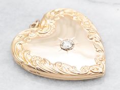 Discover the elegance of Victorian style with this heart shaped locket. The intricate scrolling design and sparkling diamond accent make it a timeless piece. Personalized with a custom "ASL" engraving and keep your loved one close to your heart! This pendant does not come with the chain shown. Don't hesitate to get in touch with us, we will help you find the perfect chain for your style and budget! Metal: 14K and 10K Yellow Gold Gem: Diamond .40 Carats, VVS2 in Clarity, I in Color Gem Measurements: 4.7 mm, Round Monogram: "ALS" Engraved Measurements: 40 x 49 mm, with bail SKU #: A52684 Each piece has been identified and graded by a Graduate Gemologist who has been certified by the Gemological Institute of America (GIA). We have six brick-and-mortar storefronts in Maine, Massachusetts, and Round Monogram, Heart Shaped Locket, Diamond Locket, Sparkling Diamond, Colored Gems, Heart Locket, Locket Necklace, Sparkle Diamonds, Diamond Heart