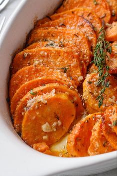 a white casserole dish filled with sliced oranges and parmesan cheese