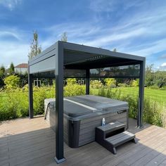 a hot tub sitting on top of a wooden deck next to a lush green field