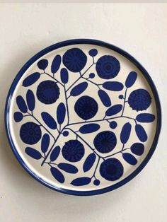 a blue and white plate sitting on top of a table next to a wall mounted clock