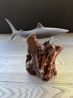 a shark figurine sitting on top of a piece of wood