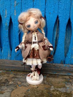 a doll with blonde hair and blue eyes is standing in front of a blue door