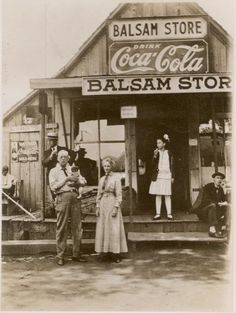 an old black and white photo of people standing in front of a store with coca cola