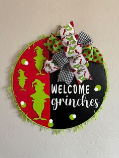 a welcome sign hanging on the wall with green and red ribbons attached to it's sides