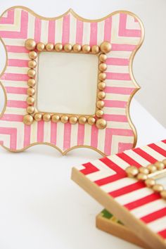 a pink and white striped frame sitting on top of a table next to a mirror