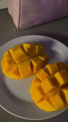 two pieces of mango sitting on top of a white plate next to a pink bag