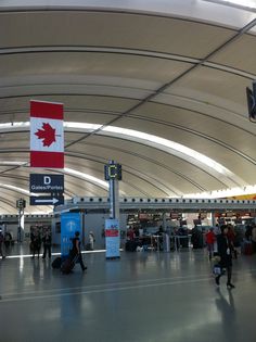 people are walking through an airport terminal with luggage and signs on the wall above them