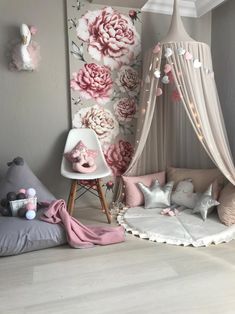 a child's bedroom decorated in pink and grey with flowers on the wall behind it