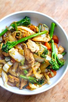 a white bowl filled with meat and veggies on top of a wooden table