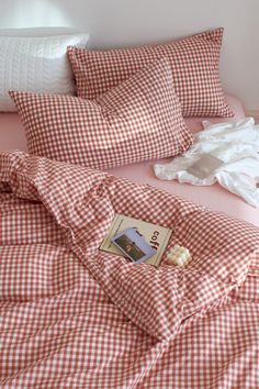 an unmade bed with red and white checkered sheets