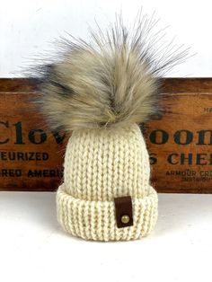 These are adorable little folded brim hats adorned with mini unstuffed faux fur poms.The hats measure 4" tall (not including the pom) x 3" Made from 100% wool yarn with suede tags, metal rivets and a suede tie for hanging.Listing is for 1 Mini Hat Ornament Handmade Beige Hat For Fall, Cute Cream Hat For Gift, Adjustable Knitted Beige Beanie, Adjustable Cream Hat For Gifts, Adjustable Knitted Cream Beanie, Adjustable Cream Hat For Gift, Adjustable Cream Hat As Gift, Adjustable Warm Cream Beanie, Adjustable Cozy Beige Beanie