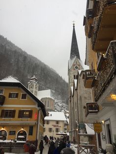 people are walking in the snow near buildings and a church with a steeple on top