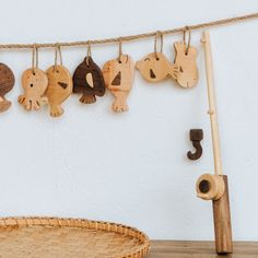 several wooden animals hanging on a rope next to a woven basket and wall hooks