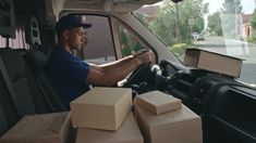 a man sitting in the driver's seat of a truck filled with boxes