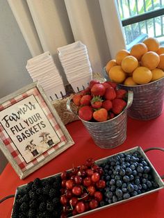 a table topped with metal buckets filled with fruit