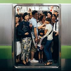 a group of people standing on a subway platform next to an open door with their arms around each other