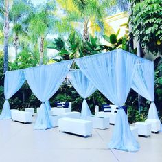 an outdoor wedding setup with white couches and blue drapes