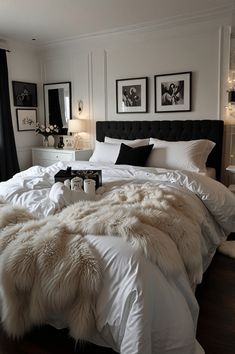 a bedroom with white bedding, black and white decor and pictures on the wall