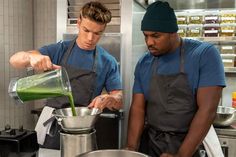 two men in aprons are preparing food in a kitchen