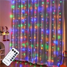 a remote control sitting on top of a wooden floor next to a window covered in multicolored lights