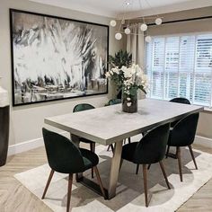 a dining room table with green chairs and a painting on the wall