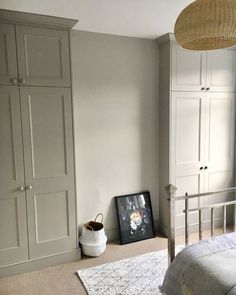 a bed room with a neatly made bed and white cupboards