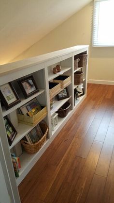 an empty room with wooden floors and white bookcases