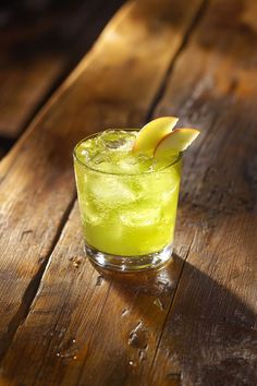 a drink with an apple on the rim sitting on a wooden table