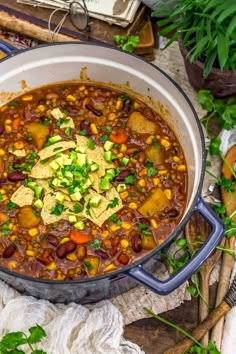 a large pot filled with beans, corn and tortilla chips on top of a wooden cutting board