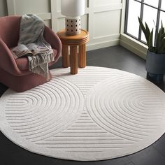 a round rug in the middle of a living room with a chair and potted plant