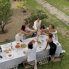 a group of people standing around a table with food on it