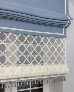 a blue and white roman blind hanging on the side of a window