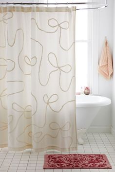 a bath room with a shower curtain and a rug on the floor in front of a tub