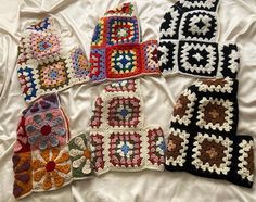 six crocheted grannys are arranged on a white sheet, one has a flower in the center