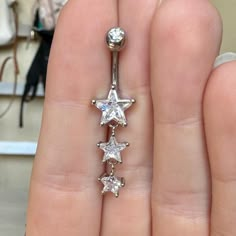 a person's hand holding an open belly ring with five stars on the side