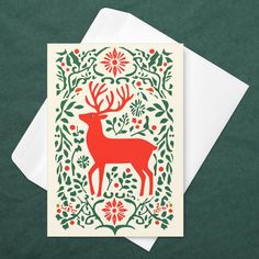 a card with an image of a red deer surrounded by holly and berries, on a green background