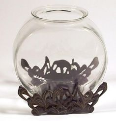 a clear glass vase with some black metal decorations in the bottom and sides, on a white background